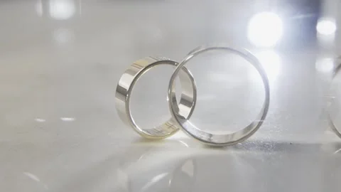Two gold wedding rings on a light surface and in the reflection of lenses with a Stock Footage 306145201