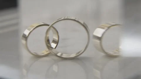 Two gold wedding rings on a light surface and in the reflection of lenses with a Stock Footage 306145215
