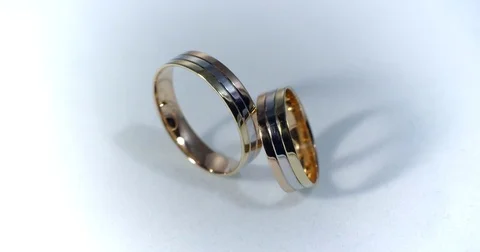 Two gold wedding rings lying on white-gray surface shining with light close up Stock Footage 77080265