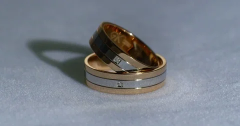 Two gold wedding rings lying on white-gray surface shining with light close up Video stock 77081060