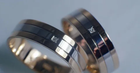 Two gold wedding rings lying on white-gray surface shining with light close up Stock-Footage 77081388