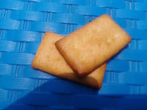 Two golden biscuits on blue background. Stock Photos