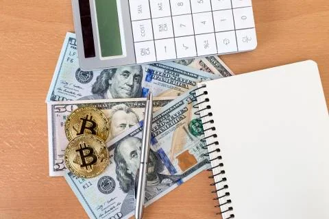 Two golden bitcoins, journal, pen, and calculator on us dollars top view Stock Photos