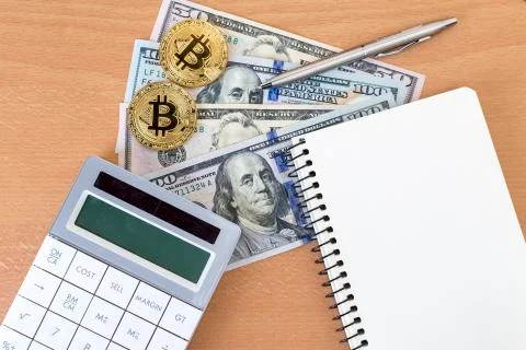 Two golden bitcoins, journal, pen, and calculator on us dollars top view Stock Photos
