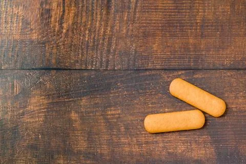 Two golden finger biscuits on rustic wooden background with copy space Stock Photos
