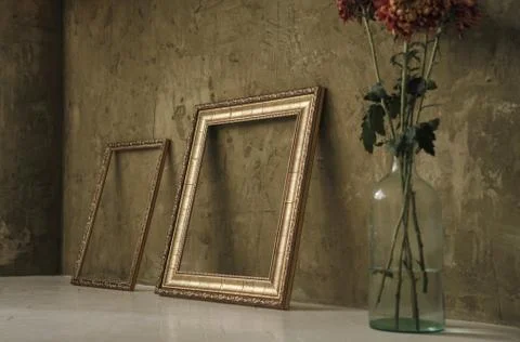 Two golden frames on the floor and flower vase Foto stock