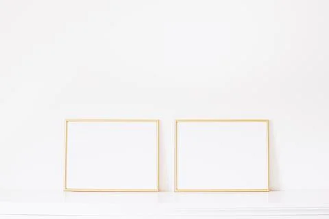 Two golden horizontal frames on white furniture, luxury home decor and design Stock Photos