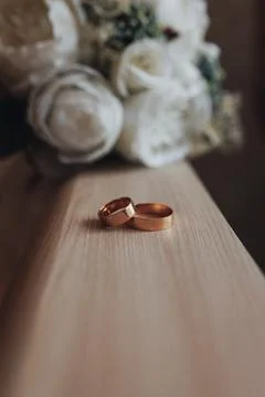 Two golden rings rest side by side on a wooden surface Foto stock