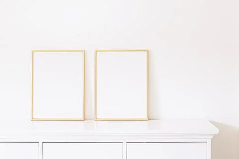 Two golden vertical frames on white furniture, luxury home decor and design for Stock Photos