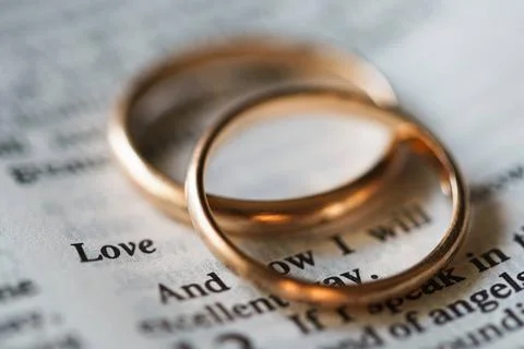 Two golden wedding rings and opened pages of holy bible represents the con... Stock Photos