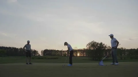 Two golfers with junior golfers walking on perfect golf course at sunset day Stock Footage 95918668