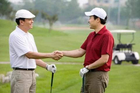 Two golfers shaking hands on the course Stock Photos