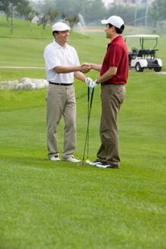 Two golfers shaking hands on the course Stock Photos