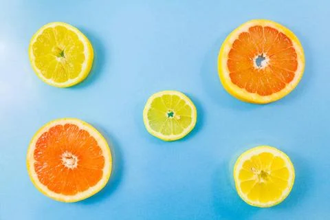 Two grapefruit and three lemon slices on blue background. Top view of two ... Foto stock