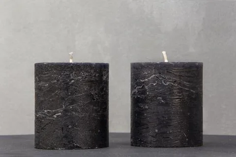 Two gray candles on a table on a wall background Stock Photos