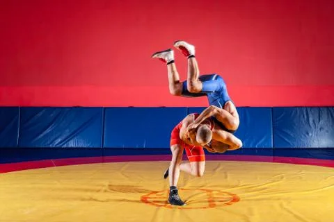 Two greco-roman  wrestlers in red and blue uniform wrestling   on a yellow wr Stock Photos