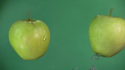 Two green apples are flying and raising splashes of water in slow motion Stock Footage 129117025