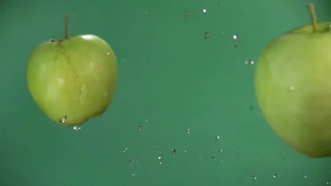 Two green apples are flying towards each other, colliding on green background Stock Footage 234051472