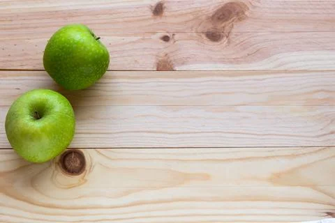 Two green apples sit on a light wooden surface Stock Photos