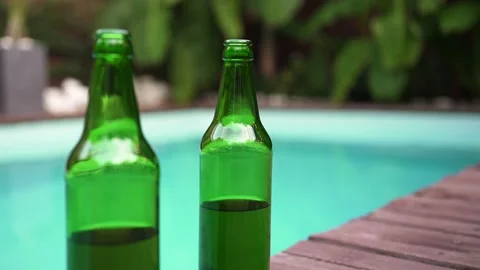 Two green bottles of beer without a logo outside. Swimming pool in the tropics Stock Footage 160813609