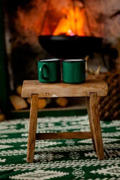 Two green cups stand on a stool against the background of the hearth in the c Stock Photos