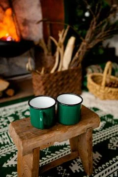 Two green cups stand on a stool against the background of the hearth in the c Stock Photos