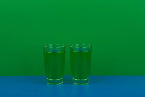 Two green drinks on blue table against green background with space for text Stock Photos