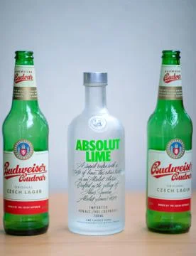 Two green empty Budweiser beer bottles and vodka Absolut Lime. Stock Photos