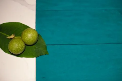 Two green nuts and a leaf on a blue-white background Stock Photos