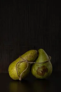 Two green pears are positioned upright against a dark backdrop. Foto stock
