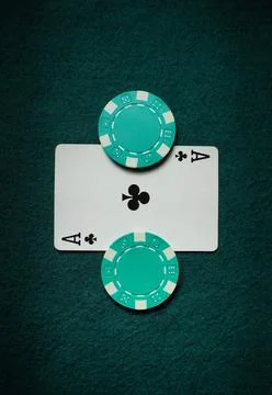 Two green poker chips sit next to an ace of clubs card on green felt. This sc Stock Photos