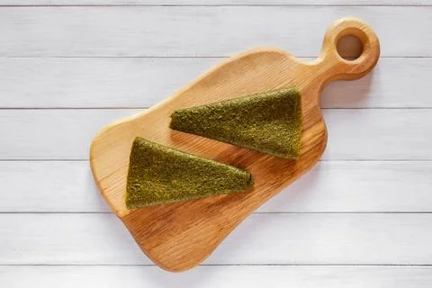 Two green triangular fruit pastille pieces placed on a wooden cutting board.. Stock Photos