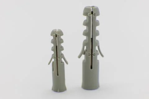 Two grey wall plugs, one larger than the other, are displayed against a white Stock Photos