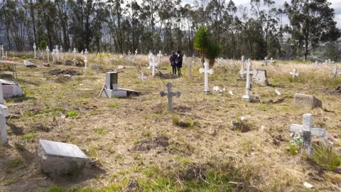 Two grieving women visiting relatives graves in a rural cemetery Stock Footage 339347635