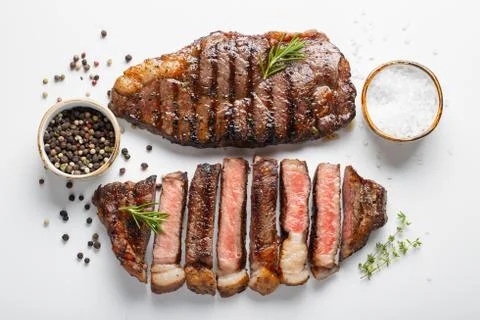 Two grilled marbled beef steaks striploin with spices isolated on white backg Stock Photos