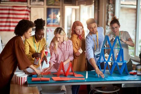Two groups of employees making paper towers, separated in different competiti 스톡 사진
