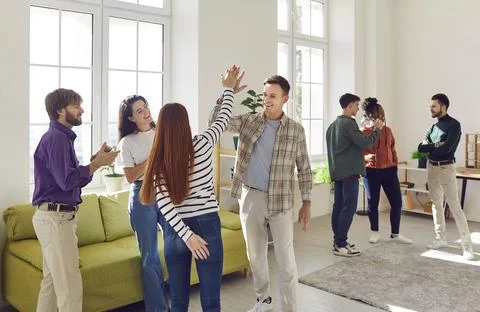 Two groups of happy looking friends standing and chatting in big spacious room Foto stock