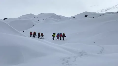 Two groups of hikers climbers are walking along the snow trail Stock Footage 141050199
