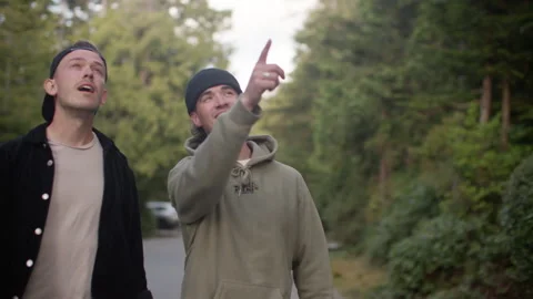 Two guy friends walk down beautiful tree surrounding road amazed by beauty 库存影片 206470782