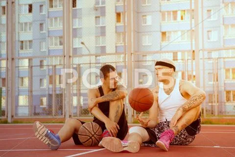Two Guys Are Sitting On The Basketball Court
