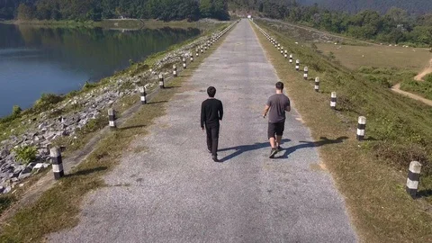 Two guys are walking beside a lake in chiang mai Stock Footage 100988975