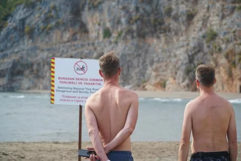 Two guys on the beach read the rules of conduct Stock Photos
