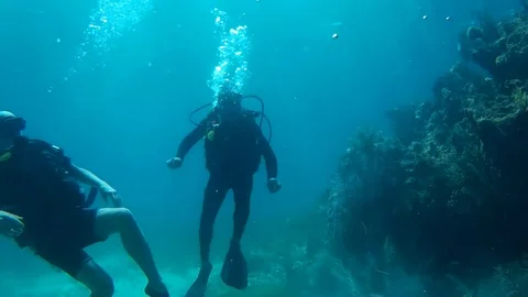 Two guys carefully navigate while doing sign language through blue waters Vidéo 95877072