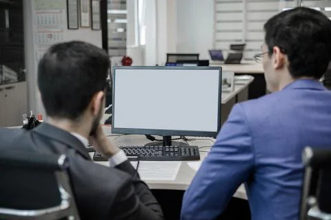 Two guys at a computer in the call center behind the counter. Stock Photos