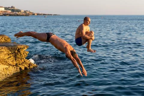 Two guys diving from a cliff Stock Photos