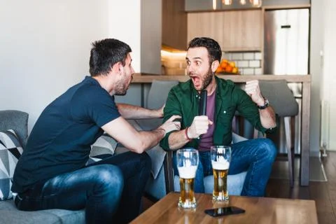 Two guys drinking beer watching football Stock Photos