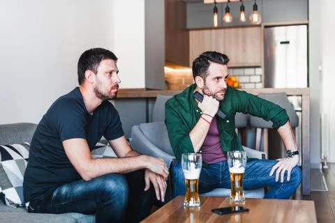 Two guys drinking beer watching football Stock Photos
