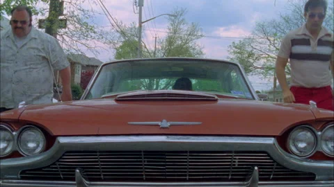 Two guys get out of a thunderbird and switch seats Stock Footage 273401948