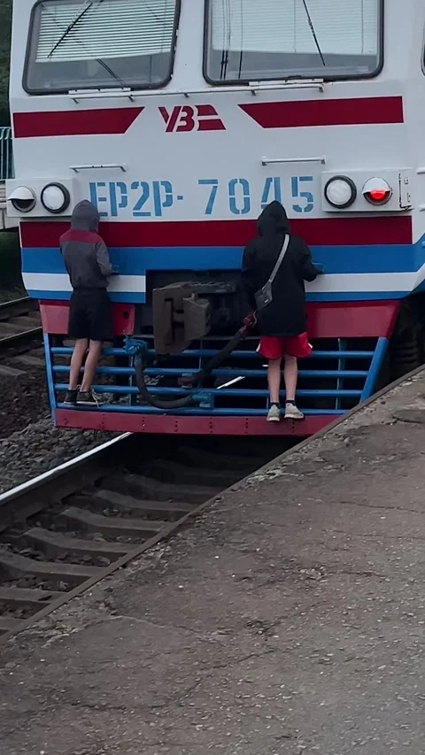 Two guys have hitched to the back car of an electric train and are riding it Video stock 322099304