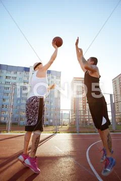Two Guys Jump Stretch To The Ball On The Basketball Court. Solar Flare In The